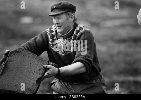 Ein Mann, der auf einem Landstrich auf der Insel Lewis in den äußeren Hebriden, Schottland, Torf schneidet. Torfschnitt war eine traditionelle Methode, um Brennstoff für den Winter in den dünn besiedelten Gebieten an Schottlands Westküste und Inseln zu sammeln. Der Torf wurde getrocknet und in Bränden und Öfen verwendet. Stockfoto