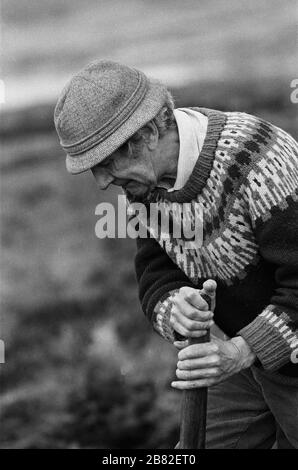 Ein Mann, der auf einem Landstrich auf der Insel Lewis in den äußeren Hebriden, Schottland, Torf schneidet. Torfschnitt war eine traditionelle Methode, um Brennstoff für den Winter in den dünn besiedelten Gebieten an Schottlands Westküste und Inseln zu sammeln. Der Torf wurde getrocknet und in Bränden und Öfen verwendet. Stockfoto