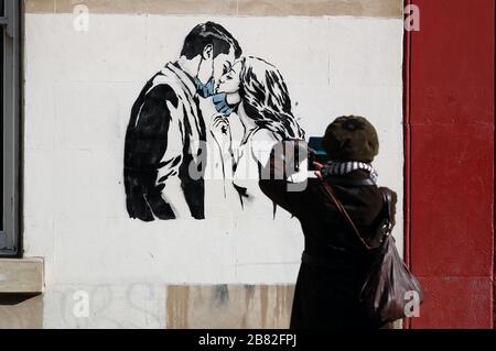Ein Kunstwerk des Künstlers, bekannt als Rebel Bear, ist an einer Wand in der Bank Street in Glasgow aufgetaucht. Die neue Ergänzung zu Glasgows Straßenkunst erfasst die globale Coronavirus Krise. Das Stück zeigt eine Frau und einen Mann, der sich zurückzieht, um sich gegenseitig einen Kuss zu geben. Stockfoto