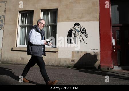 Ein Kunstwerk des Künstlers, bekannt als Rebel Bear, ist an einer Wand in der Bank Street in Glasgow aufgetaucht. Die neue Ergänzung zu Glasgows Straßenkunst erfasst die globale Coronavirus Krise. Das Stück zeigt eine Frau und einen Mann, der sich zurückzieht, um sich gegenseitig einen Kuss zu geben. Stockfoto