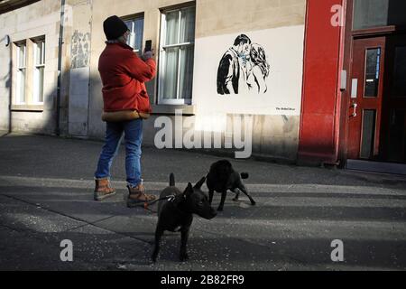 Ein Kunstwerk des Künstlers, bekannt als Rebel Bear, ist an einer Wand in der Bank Street in Glasgow aufgetaucht. Die neue Ergänzung zu Glasgows Straßenkunst erfasst die globale Coronavirus Krise. Das Stück zeigt eine Frau und einen Mann, der sich zurückzieht, um sich gegenseitig einen Kuss zu geben. Stockfoto