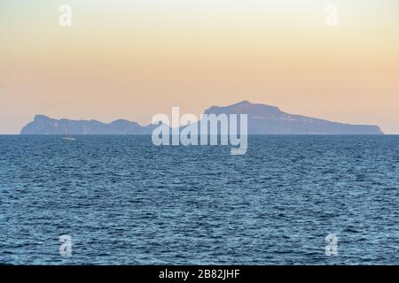 Die Insel Capri am Horizont erstreckt sich über den Golf von Neapel, der von der Küste der Stadt aus gesehen wird, in einem Landschaftsblick bei Sonnenuntergang Stockfoto