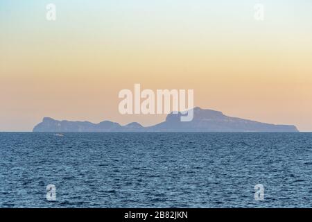 Die Insel Capri am Horizont erstreckt sich über den Golf von Neapel, der von der Küste der Stadt aus gesehen wird, in einem Landschaftsblick bei Sonnenuntergang Stockfoto