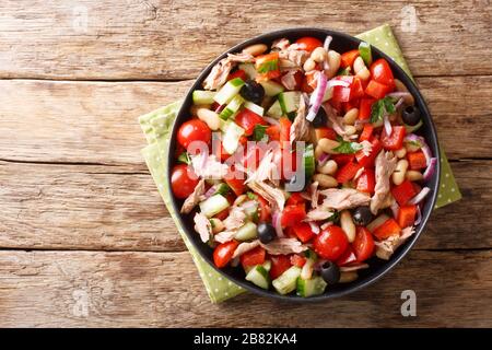 Frische Salate mit Thunfisch, Gemüse, Oliven und Bohnen werden in einem Teller auf dem Tisch serviert. Horizontale Draufsicht von oben Stockfoto