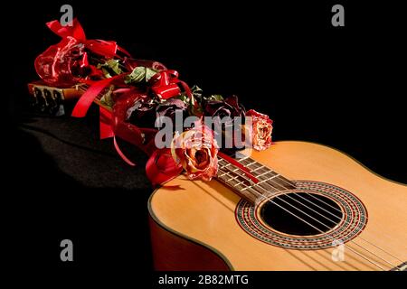 Akustische Gitarre und getrocknete Rosen auf schwarzem Hintergrund akustische Gitarre und getrocknete Rosen auf schwarzem Hintergrund Stockfoto