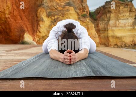 Frau, die draußen Yoga praktiziert, die Haltung des Kindes. Stockfoto