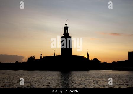 Die kultige Silhouette des Stockholmer Rathauses, während die Sonne an einem schönen warmen Sommerabend in der Hauptstadt Schwedens hinter sich geht Stockfoto