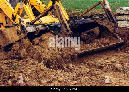 Ein Nahbagger lädt Erde in den Eimer, um die Straße weiter zu installieren. Stockfoto