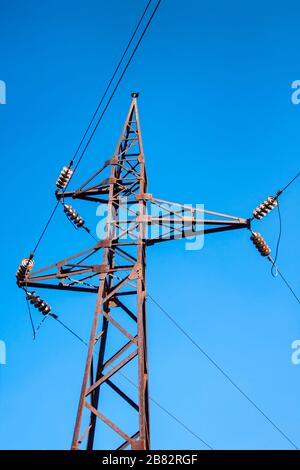 Alter rostiger Hochspannungspol vor blauem Himmel Hintergrund Stockfoto