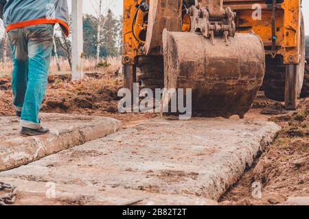 Der Bagger installiert Betonplatten für die Straße. Stockfoto