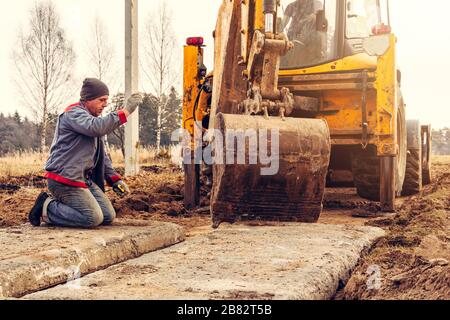 Der Bagger installiert Betonplatten für die Straße. Stockfoto