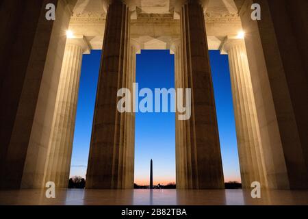 WASHINGTON, DC - BLICK von innen in die Hauptkammer des Lincoln Memorial, mit Blick durch die massiven Säulen zum Washington Monument kurz vor Sonnenaufgang. Stockfoto