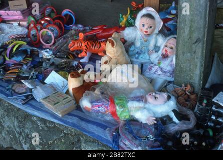 Kinderspielzeug zum Verkauf an einem Marktstand in Luang Prabang, Laos, S.E. Asien. Puppen, ein aufblasbarer Tiger, Teddybären, Haarrutschen und Spiegel sind zu sehen. Die meisten dieser Spielzeuge werden in China hergestellt. Die Stadt Luang Prabang ist ein UNESCO-Weltkulturerbe. Stockfoto