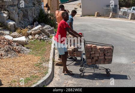 Zwelihle, Hermanus, Westkappo, Südafrika. Dezember 2019. Junge Männer sammeln alte Ziegelsteine in Einkaufswagen am Straßenrand der Gemeinde Zschweihle bei Herma Stockfoto