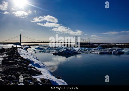 Brücke über den Fluss zum Meer, mit Eisbrocken und Eisschollen Stockfoto