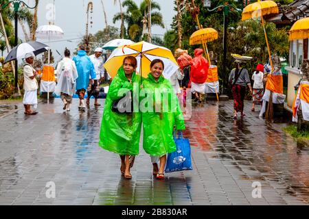 Junge Balinesische Hindu-Frauen Kommen Zur Zeremonie Batara Turun Kabeh Im Regen, Besakih-Tempel, Bali, Indonesien. Stockfoto