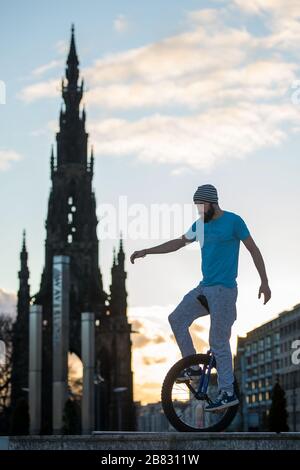 Edinburgh, Großbritannien. März 2020. Bild: Andrew Buchan, ein Stunt- und Extrem-Unicycler, vergeht die Zeit während einer normalerweise geschäftigen Hauptverkehrszeit in Edinburgh, aber aufgrund der Coronavirus Pandemie ist das Stadtzentrum extrem ruhig. Die Menschen stehen nun vor der Herausforderung, während der Selbsteingrenzung verschiedene Dinge mit ihrer Zeit zu tun. Das Scott Monument ist im Hintergrund zu sehen, das ein wichtiges Wahrzeichen von Edinburgh ist. Kredit: Colin Fisher/Alamy Live News Stockfoto