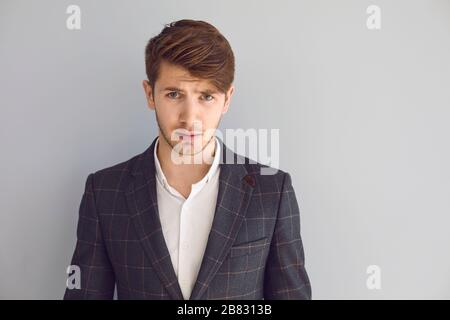 Ein ernsthafter junger Geschäftsmann, der die Kamera im Hintergrund betrachtet Stockfoto