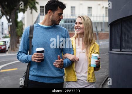 Kaukasisches Paar unterwegs in der Stadt, das einen Kaffee wegnimmt Stockfoto
