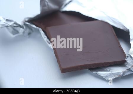 Dunkle Schokoladenstücke auf weißem Hintergrund, dicht beieinander isoliert Stockfoto