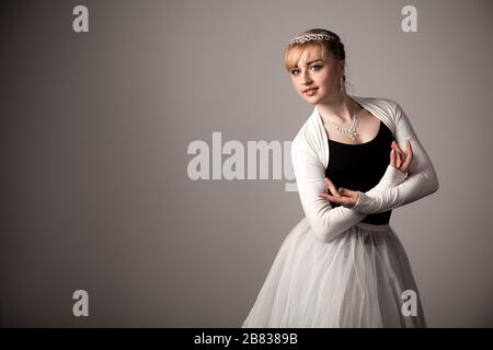 Porträt der jungen blonden Ballerina Frau in weißem Tutu und schwarz oben über weißem Hintergrund. Ballett, Anmut, Schönheit, Kunstkonzept Stockfoto