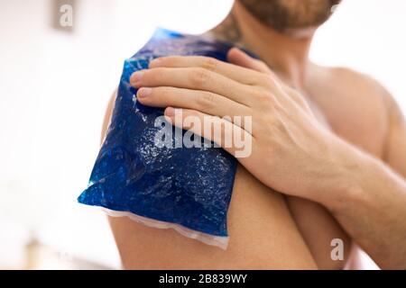 Nahaufnahme eines Mannes Anwendung Cool Gel Pack auf seiner Schulter Stockfoto