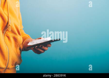Wischen Sie den Bildschirm des Smartphones mit einem Desinfektionstuch ab. Notwendige Methode, um eine Ausbreitung von Coronavirus Covid-19 zu verhindern. Stockfoto