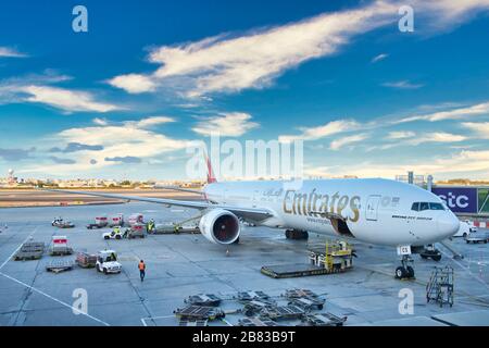 Eine Emirates Boeing 777 - 300er, das größte Passagierflugzeug der Welt, wartet bei Sonnenuntergang auf Passagiere und Verladung am Flughafen Bahrein. Stockfoto