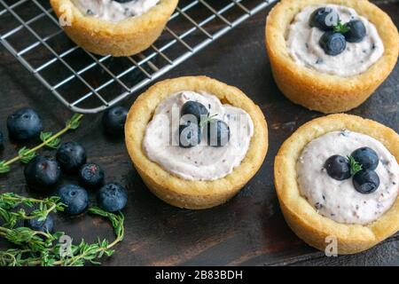 Blueberry Cheesecake Cookie Cups: Mini-Blaubeeren-Käsekuchen in Vanilleplätzchen Stockfoto