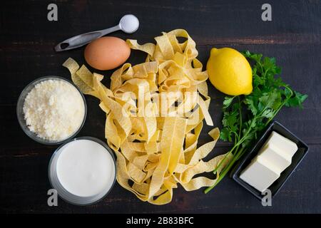 Pappardelle al Limone Zutaten: Getrocknete Pasta, Zitrone, Ei und andere Zutaten, die verwendet werden, um ein Gericht aus breiten Nudeln in einer cremigen Zitronen-Parmesan-Sauce zu machen Stockfoto