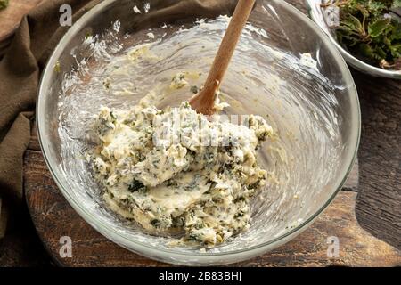 Butter gemischt mit gehackten jungen Brennnesseln - Zubereitung eines Brotes aus wilden essbaren Pflanzen Stockfoto