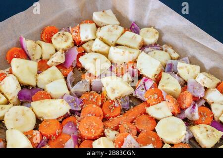 Sortiment mariniertes gewürfeltes Gemüse mit Karotte, roter Zwiebel, Parsnip und Sesamsamen auf Backpapier. Vegetarisches Ofengericht. Stockfoto