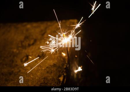 Brennender Funkenstift Sternenfeuerwerk pyrotechnische dunkle schwarze warme Hintergründe Stockfoto