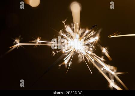 Brennender Funkenstift Sternenfeuerwerk Pyrotechnik Dunkelschwarz warmer Hintergrund an der Hand gehalten Stockfoto