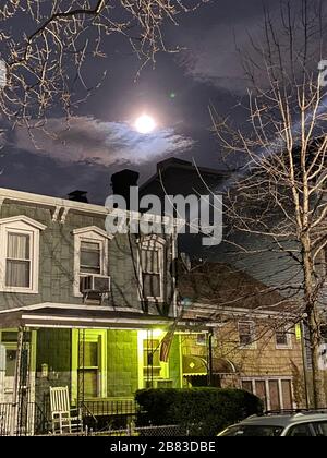 Vollmond im Zeichen der Jungfrau, die aus dem Osten über Brooklyn, New York steigt. Stockfoto