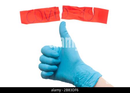 Ärzte haben Coronavirus besiegt. Konzept. Handgeste in einem medizinischen Handschuh gegenüber einer zerrissenen Aufschrift. Stockfoto