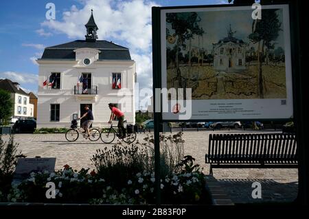 Das Rathaus von Auvers-Sur-Oise mit Menschen auf Fahrrädern und der von Vincent Van Gogh im Vordergrund gemalte Wegweiser des Rathauses. Auvers-sur-Oise.Ile-de-France.France Stockfoto