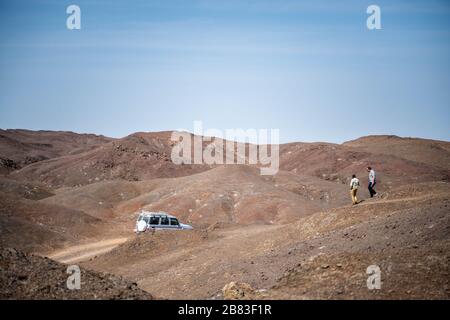 Afrika, Dschibuti, Abbe-See. Auf dem Weg zum Abbe See ist ein Geländewagen abgestellt, zwei Personen gehen einen Hügel hinunter Stockfoto