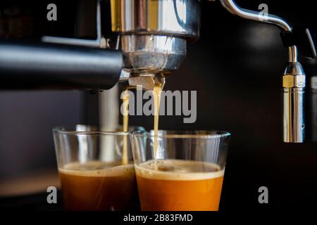 Nahaufnahme einer Kaffeemaschine, die Kaffee in Tassen gießt Stockfoto