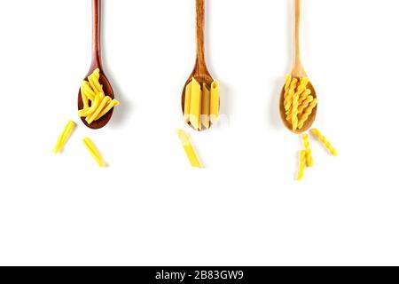 Verschiedene Arten von italienischen Nudelkonzepten. Raw gemelli, Penne, Casarecce in Holzlöffeln auf weißem Grund. Draufsicht, Kopierbereich. Stockfoto