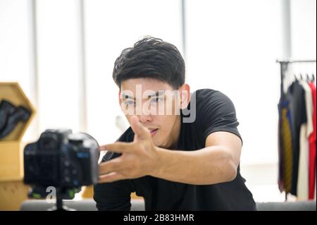 Glücklicher Mann zu Hause, der vor der Kamera für vlog spricht. Junger Asian, der als Blogger arbeitet und Videolehrgang für das Internet aufzeichnet Stockfoto