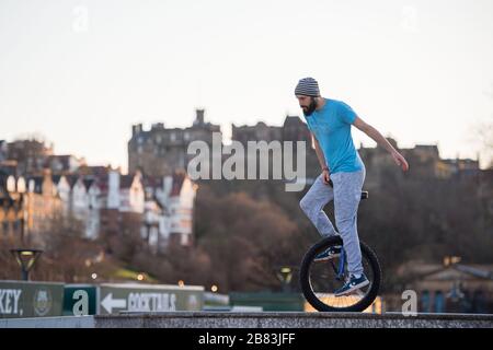 Edinburgh, Großbritannien. März 2020. Bild: Andrew Buchan, ein Stunt- und Extrem-Unicycler, vergeht die Zeit während einer normalerweise geschäftigen Hauptverkehrszeit in Edinburgh, aber aufgrund der Coronavirus Pandemie ist das Stadtzentrum extrem ruhig. Die Menschen stehen nun vor der Herausforderung, während der Selbsteingrenzung verschiedene Dinge mit ihrer Zeit zu tun. Das Scott Monument ist im Hintergrund zu sehen, das ein wichtiges Wahrzeichen von Edinburgh ist. Kredit: Colin Fisher/Alamy Live News Stockfoto