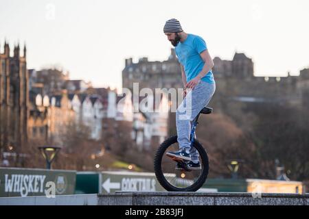 Edinburgh, Großbritannien. März 2020. Bild: Andrew Buchan, ein Stunt- und Extrem-Unicycler, vergeht die Zeit während einer normalerweise geschäftigen Hauptverkehrszeit in Edinburgh, aber aufgrund der Coronavirus Pandemie ist das Stadtzentrum extrem ruhig. Die Menschen stehen nun vor der Herausforderung, während der Selbsteingrenzung verschiedene Dinge mit ihrer Zeit zu tun. Das Scott Monument ist im Hintergrund zu sehen, das ein wichtiges Wahrzeichen von Edinburgh ist. Kredit: Colin Fisher/Alamy Live News Stockfoto