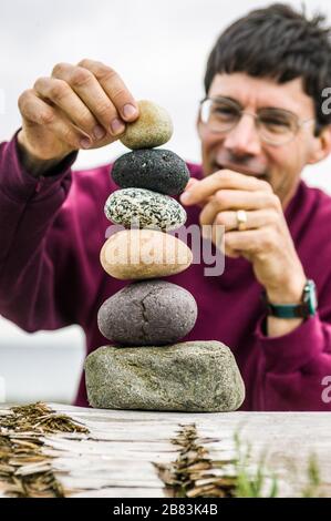 Ein Mann, der Steine übereinander balanciert. Stockfoto