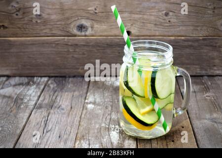 Zitronengurkendetox Wasser in einem Maurerglas mit Strohhalm vor rustikalem Holzhintergrund Stockfoto