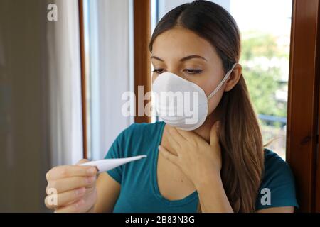 COVID-19 Pandemie Coronavirus Halsschmerzen trockenes Hustenfieber Sorgen Frau Temperaturkontrolle mit Thermometer zu Hause Symptom von SARS-COV-2. Mädchen prüfen Stockfoto