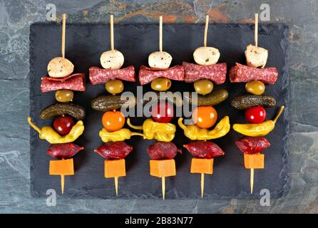 Spieß-Vorspeisen mit Käse, Fleisch und Pickeln über dem Blick auf einen Schieferserver Stockfoto