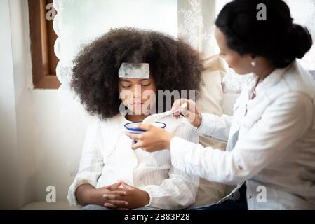 Afroamerikanische Leute, Mutter kümmert sich um eine kranke Tochter Stockfoto