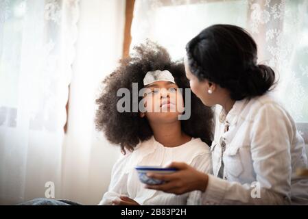 Afroamerikanische Leute, Mutter kümmert sich um eine kranke Tochter Stockfoto