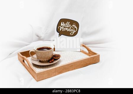 Frischer Morgenkaffee mit "Hello Monday"-Angebot auf einem Bettlaken Stockfoto